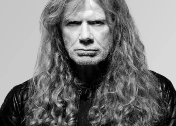 Black-and-white portrait of Dave Mustaine with long curly hair and a black leather jacket against a light grey background