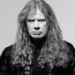 Black-and-white portrait of Dave Mustaine with long curly hair and a black leather jacket against a light grey background