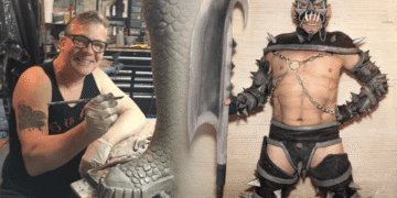 GWAR co-founder Chuck Varga Sexecutioner smiling while sculpting a scaly clay piece in his workshop, next to a performer in a spiked GWAR costume holding a giant axe