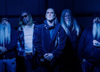 Down band members posing in dark clothing under deep blue lighting