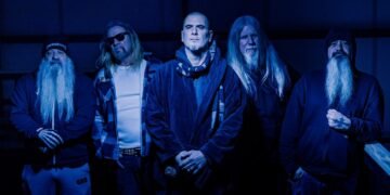 Down band members posing in dark clothing under deep blue lighting