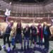 Iron Maiden celebrating on stage with guitars raised in front of a packed stadium crowd